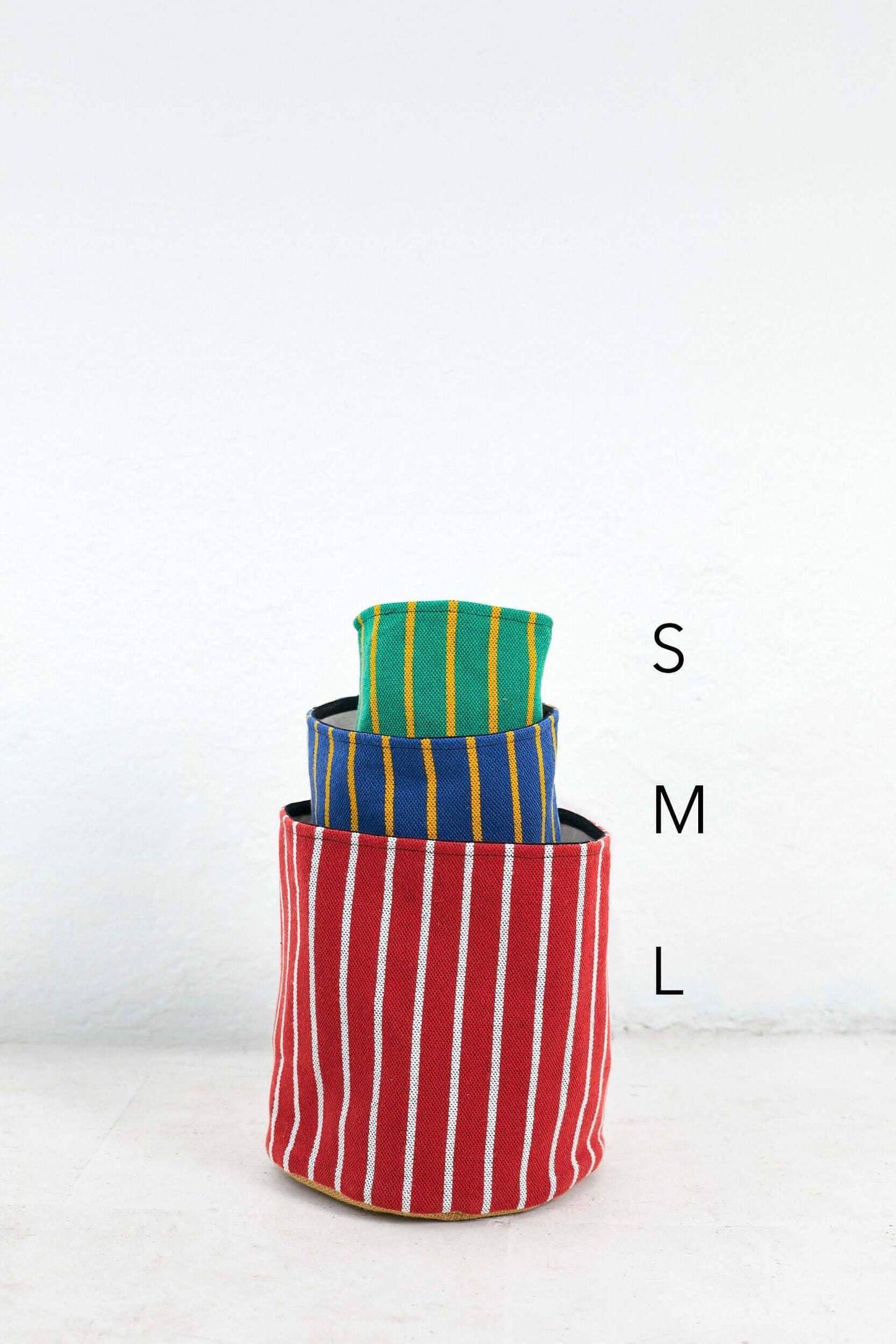 Set de tres cestos de algodón cilíndricos con diseño de rayas verticales en colores rojo, azul y verde.