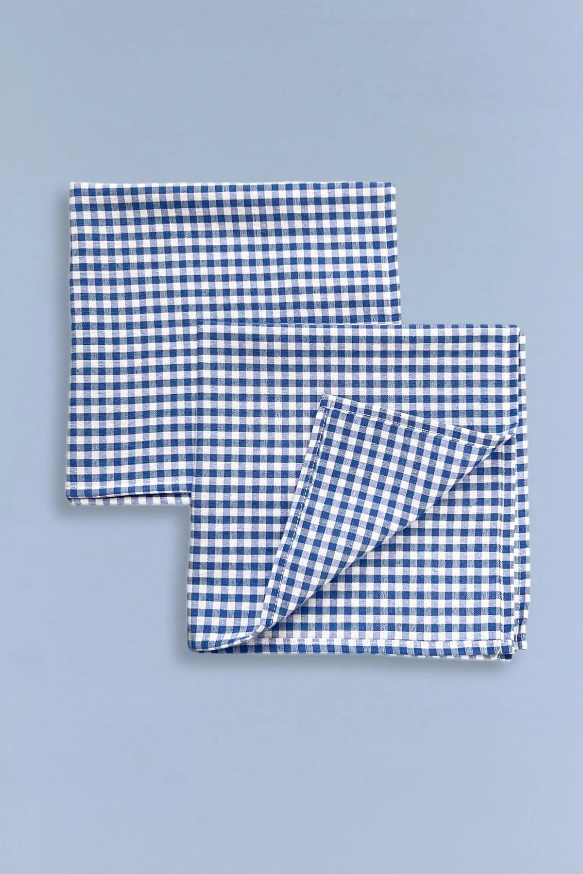 Pack de dos servilletas de tela con estampado de cuadros vichy en azul y blanco sobre fondo azul claro.