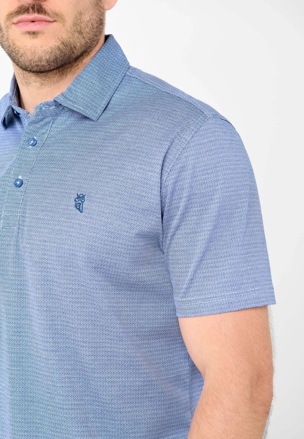 Polo azul de manga corta con patrón geométrico fino, cuello clásico, botones y logo de búho bordado en el pecho.
