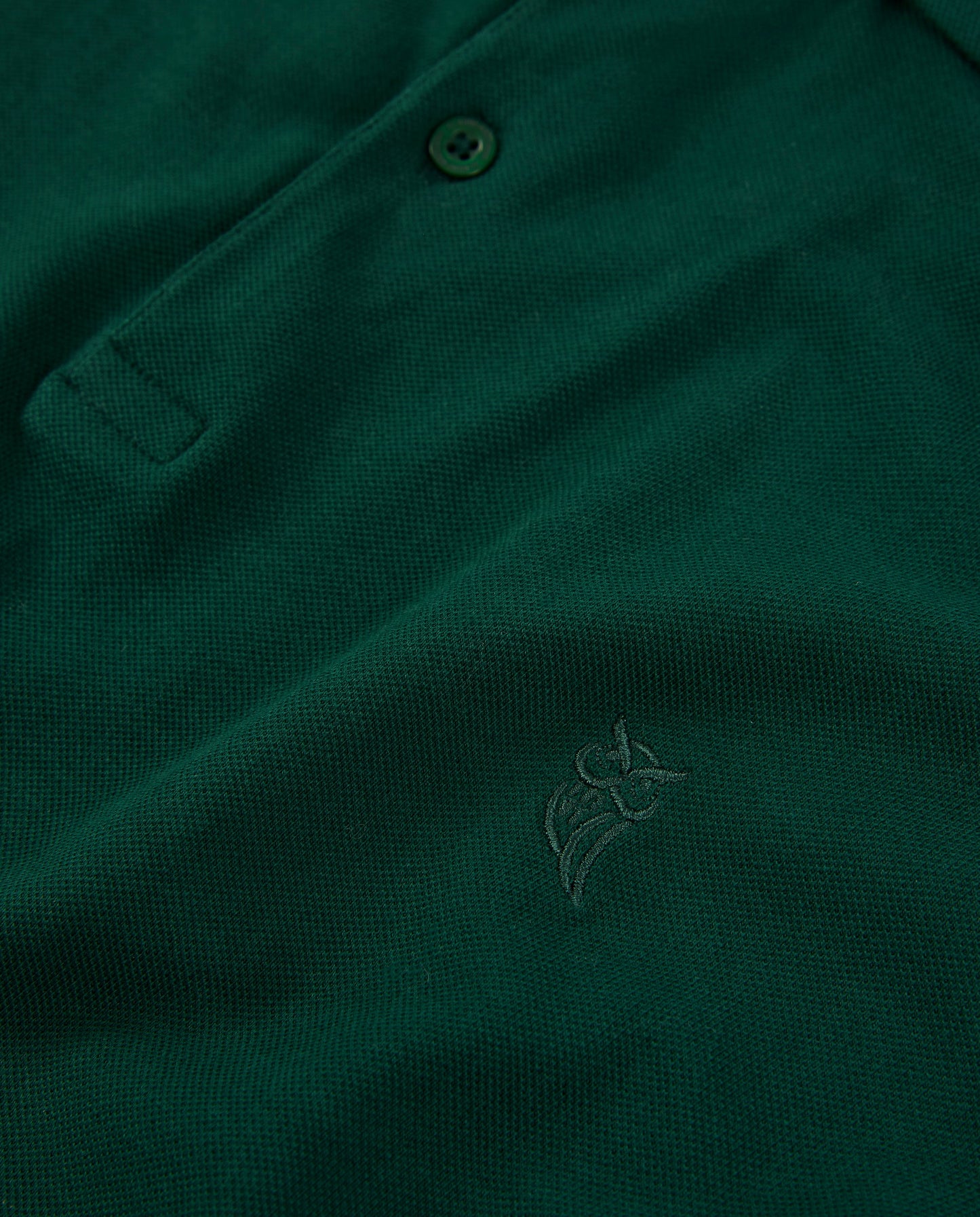 Polo de hombre verde oscuro, tejido de piqué, con bordado discreto y botones en la parte delantera.