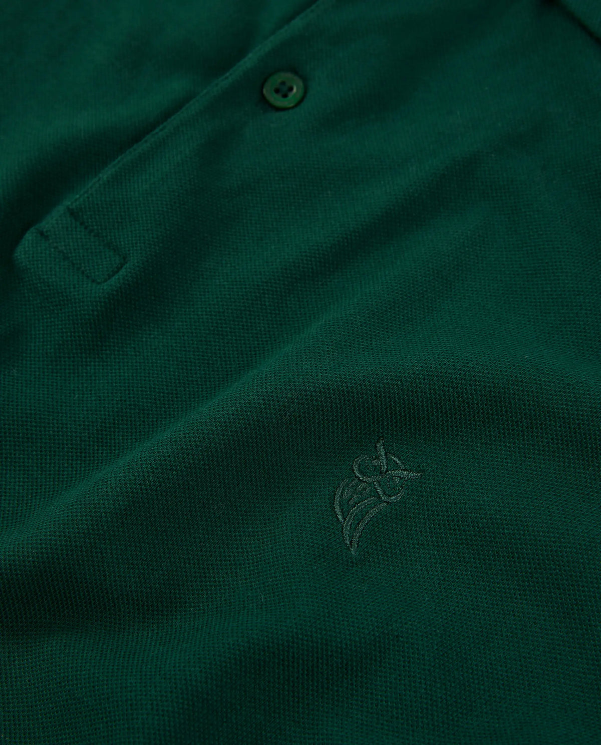 Polo de hombre verde oscuro, tejido de piqué, con bordado discreto y botones en la parte delantera.
