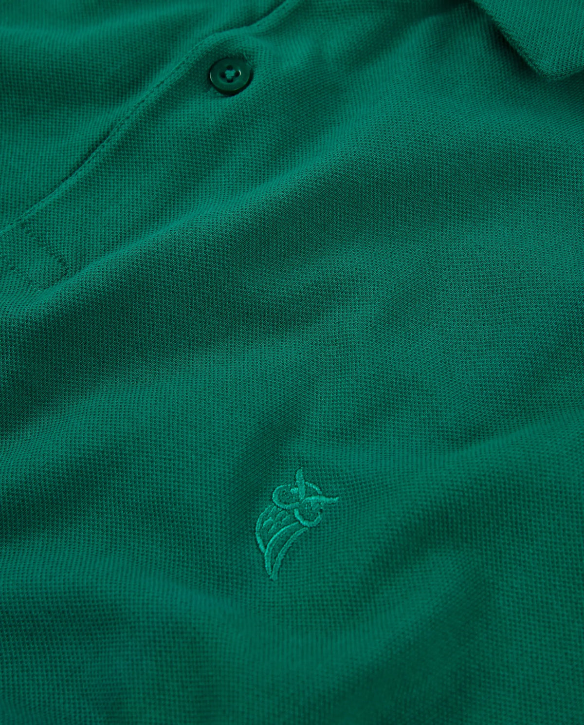 Polo verde de algodón con diseño bordado en tono a juego, estilo clásico y elegante.