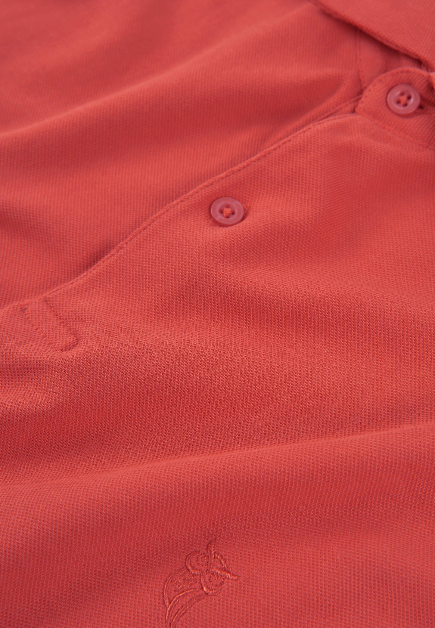 Polo de algodón pique en color coral con botones tonales y bordado en el pecho. Perfecto para un look casual.