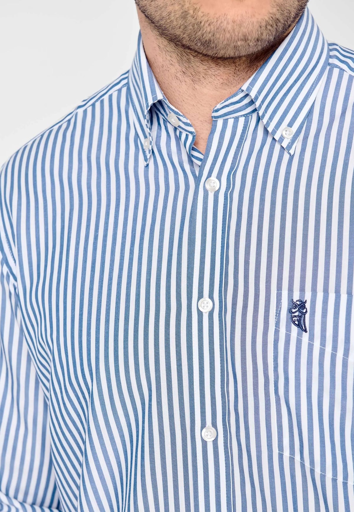 Camisa de hombre de manga larga en popelín de rayas azules y blancas, con cuello abotonado y bolsillo frontal.
