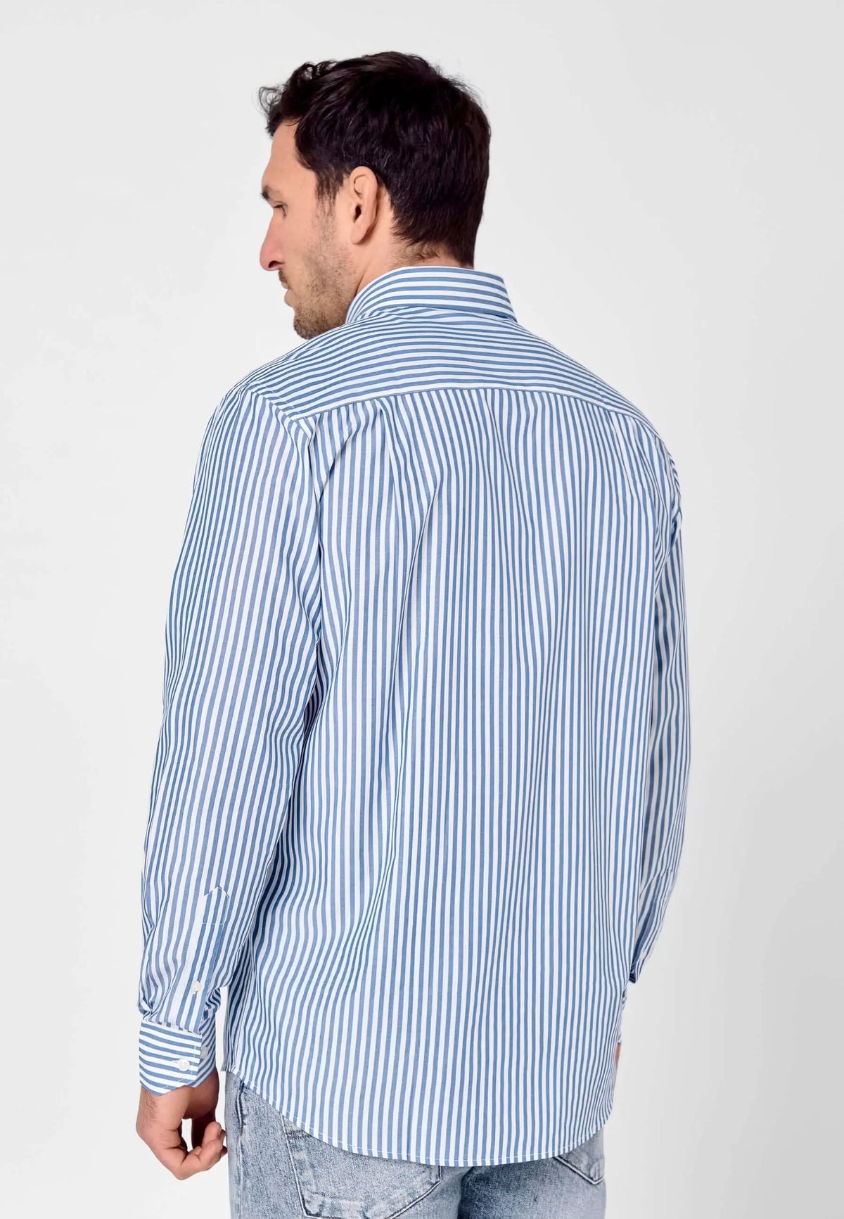 Hombre de espaldas vistiendo camisa de manga larga en popelín de rayas azules y blancas, corte clásico y extrasuave.