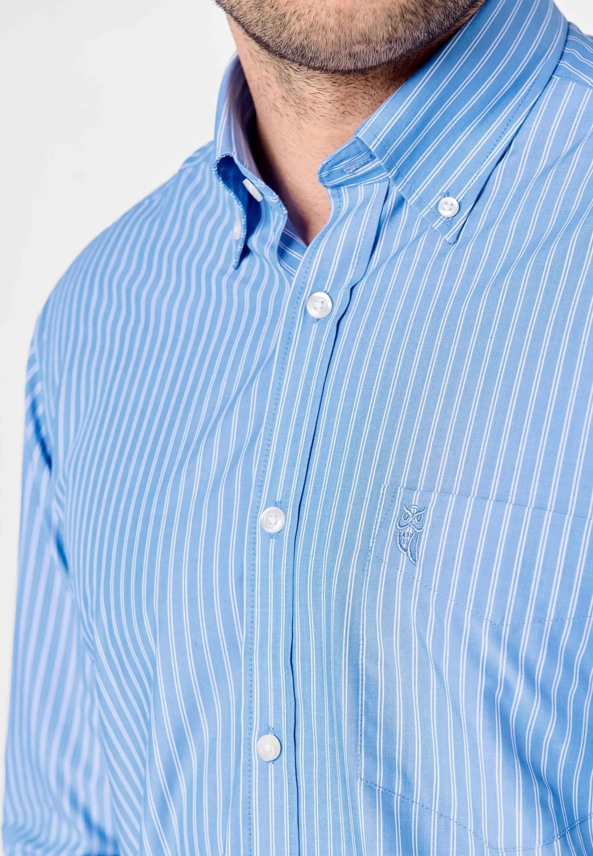 Camisa de hombre de manga larga en popelín azul a rayas blancas, corte clásico con bolsillo y cuello abotonado.