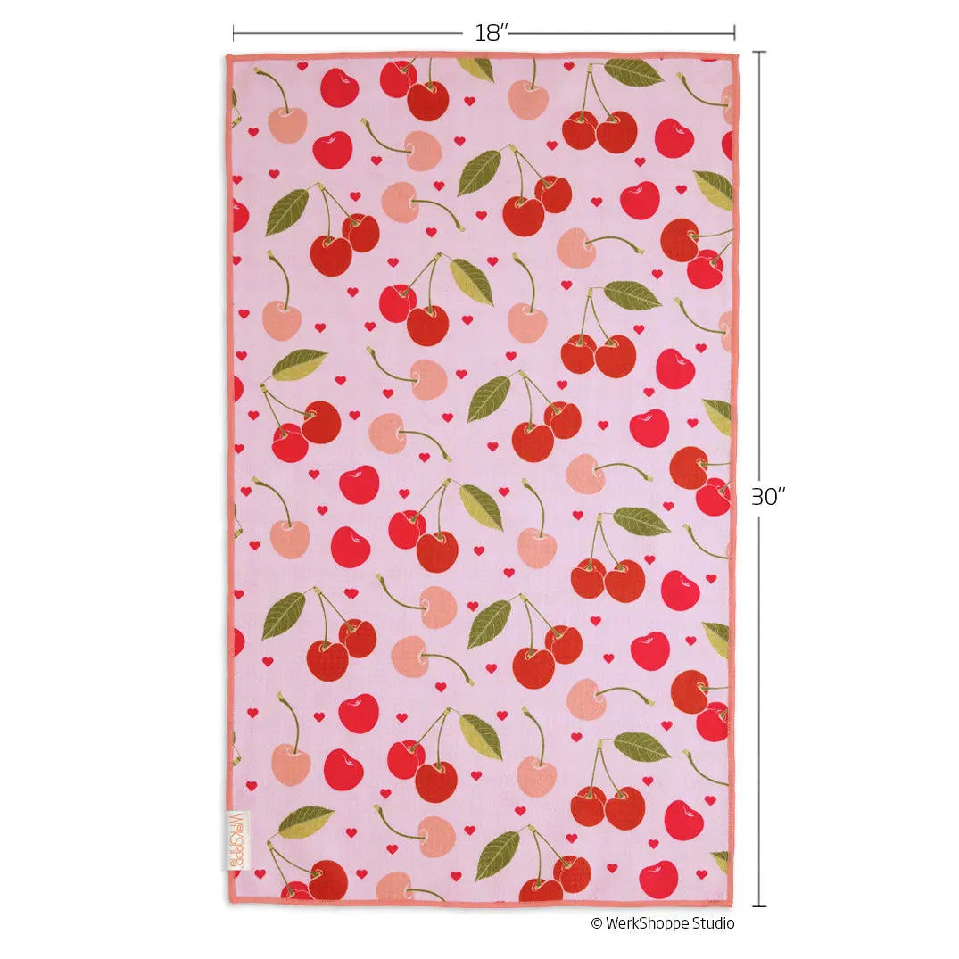 Pink microfiber kitchen towel featuring a pattern of red cherries, light pink cherries, green leaves, and tiny hearts.