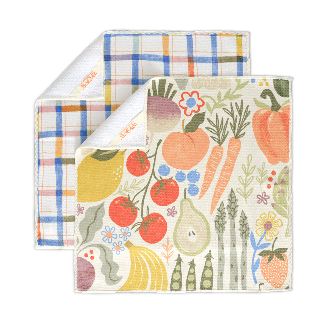 Two textured towels: one with a blue and orange plaid pattern, the other featuring colorful fruit and vegetable prints.