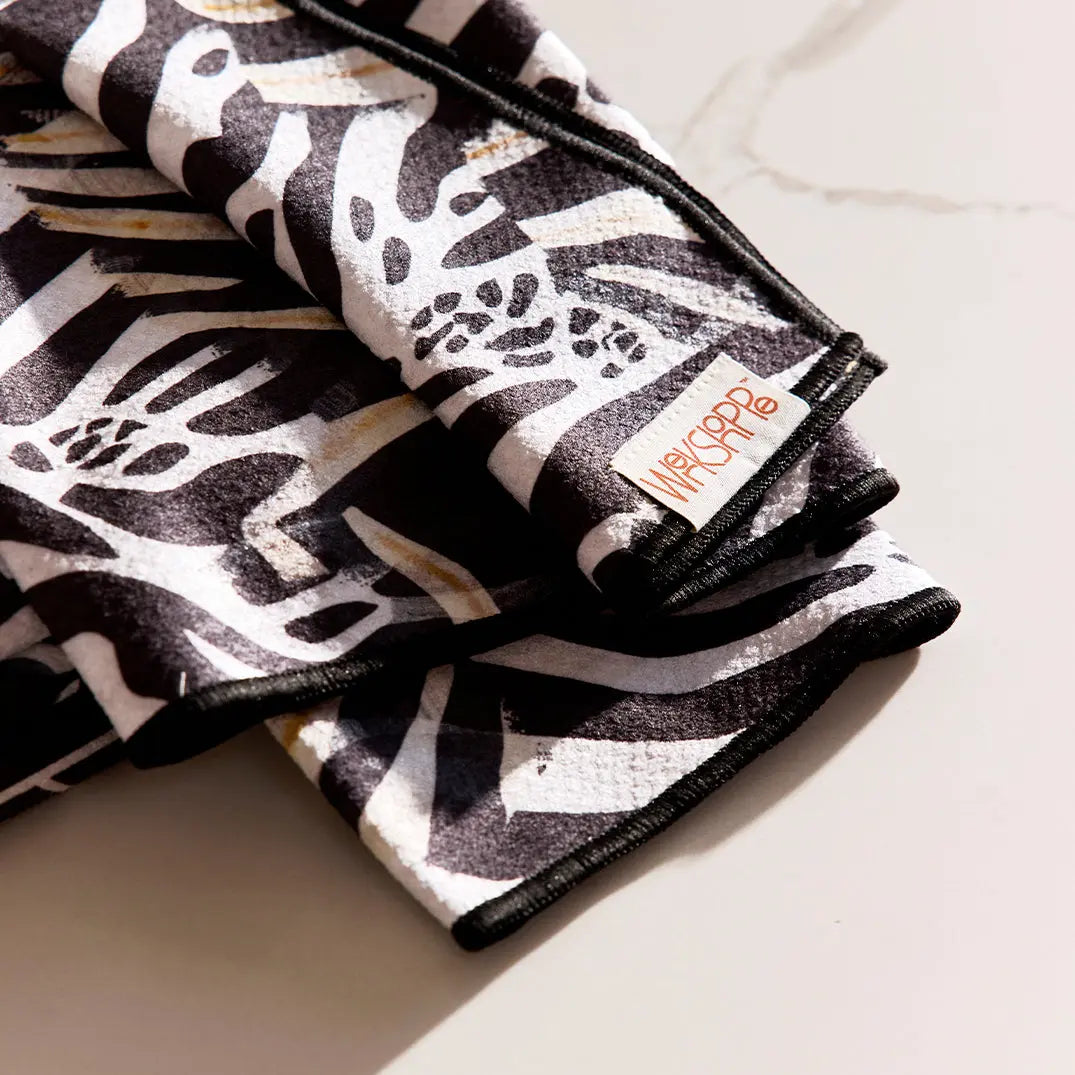 Microfiber towel with a black and white mod floral tile pattern, black stitched edges, and a WerkShoppe brand tag.