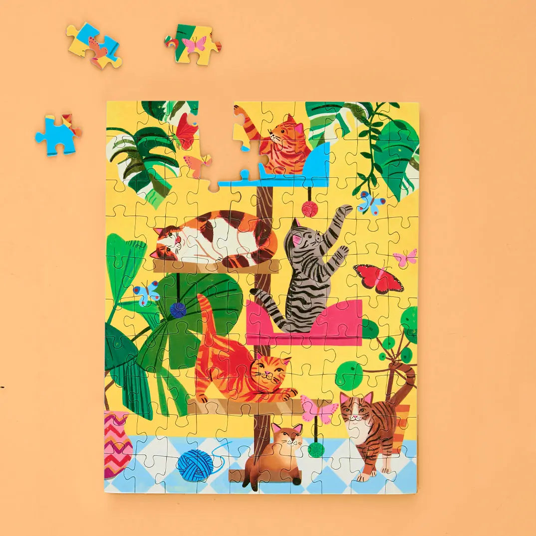 100-piece puzzle showing colorful cats playing on a cat tree with tropical plants, butterflies, and yarn balls.