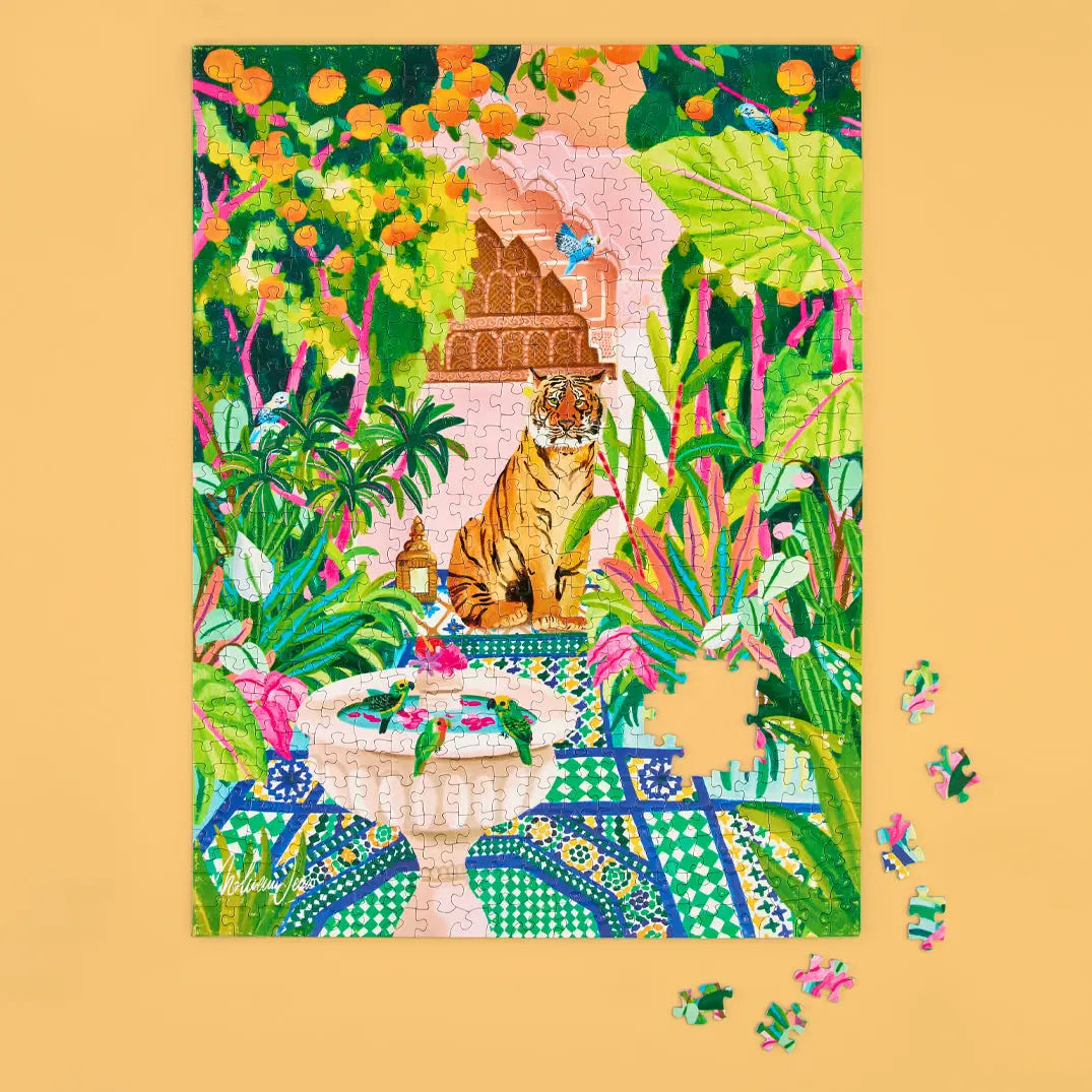 A colorful 500-piece puzzle featuring a tiger in a lush tropical garden with a fountain, birds, and orange trees.