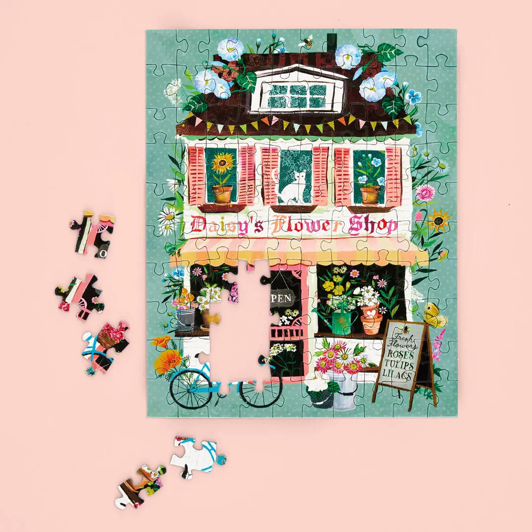 Daisy's Flower Shop 100-piece puzzle showing a whimsical illustrated building with a blue bike and floral shop sign.