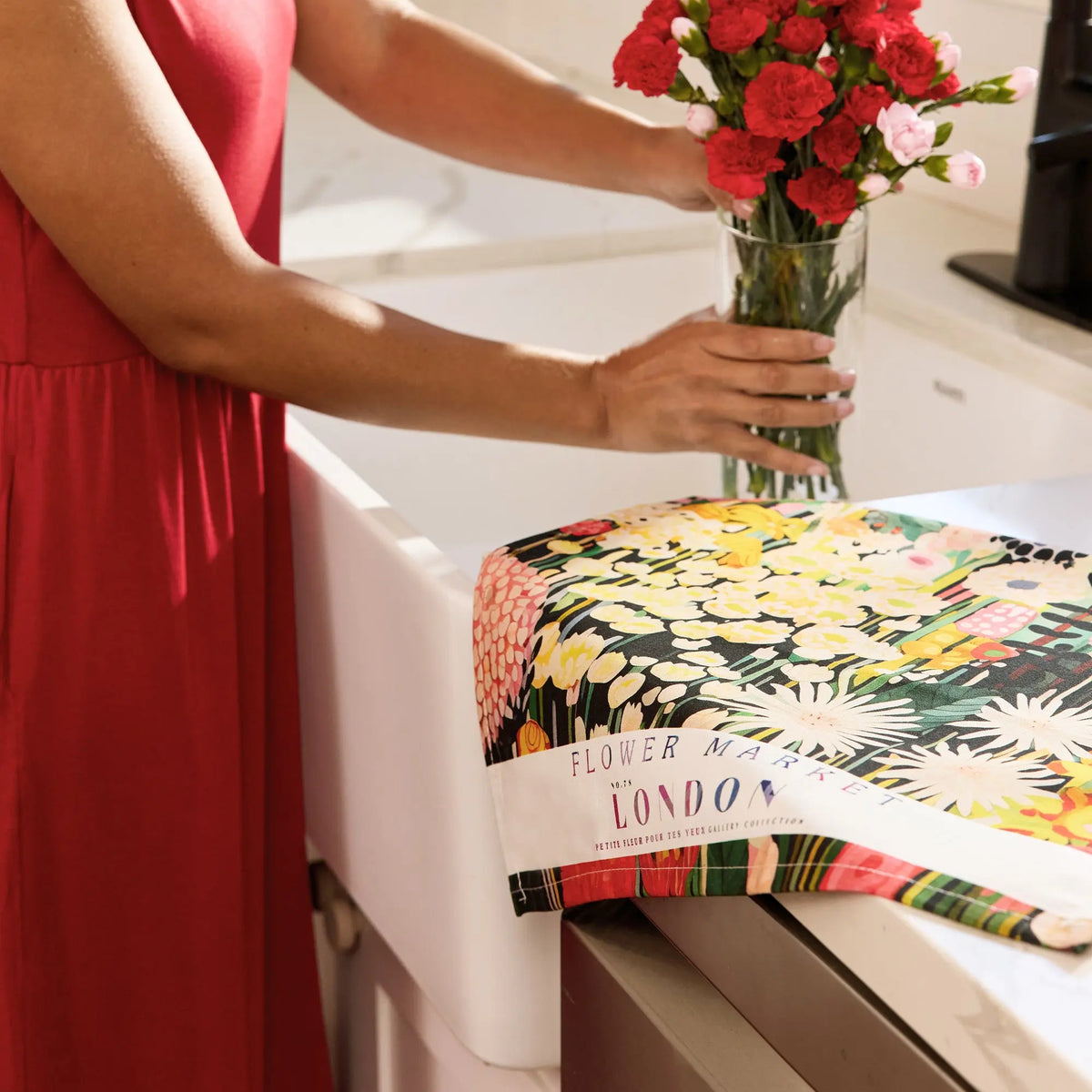 Cotton tea towel with a colorful floral print and "Flower Market London" text draped over a kitchen counter.