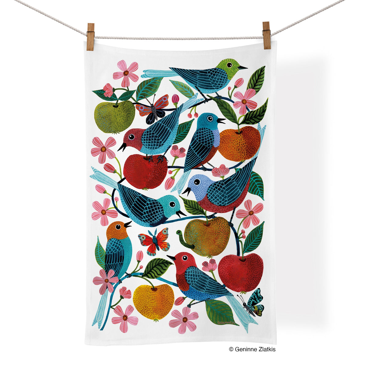 Rectangular white cotton tea towel hanging on a line, featuring an illustration of colorful birds, apples, and flowers.
