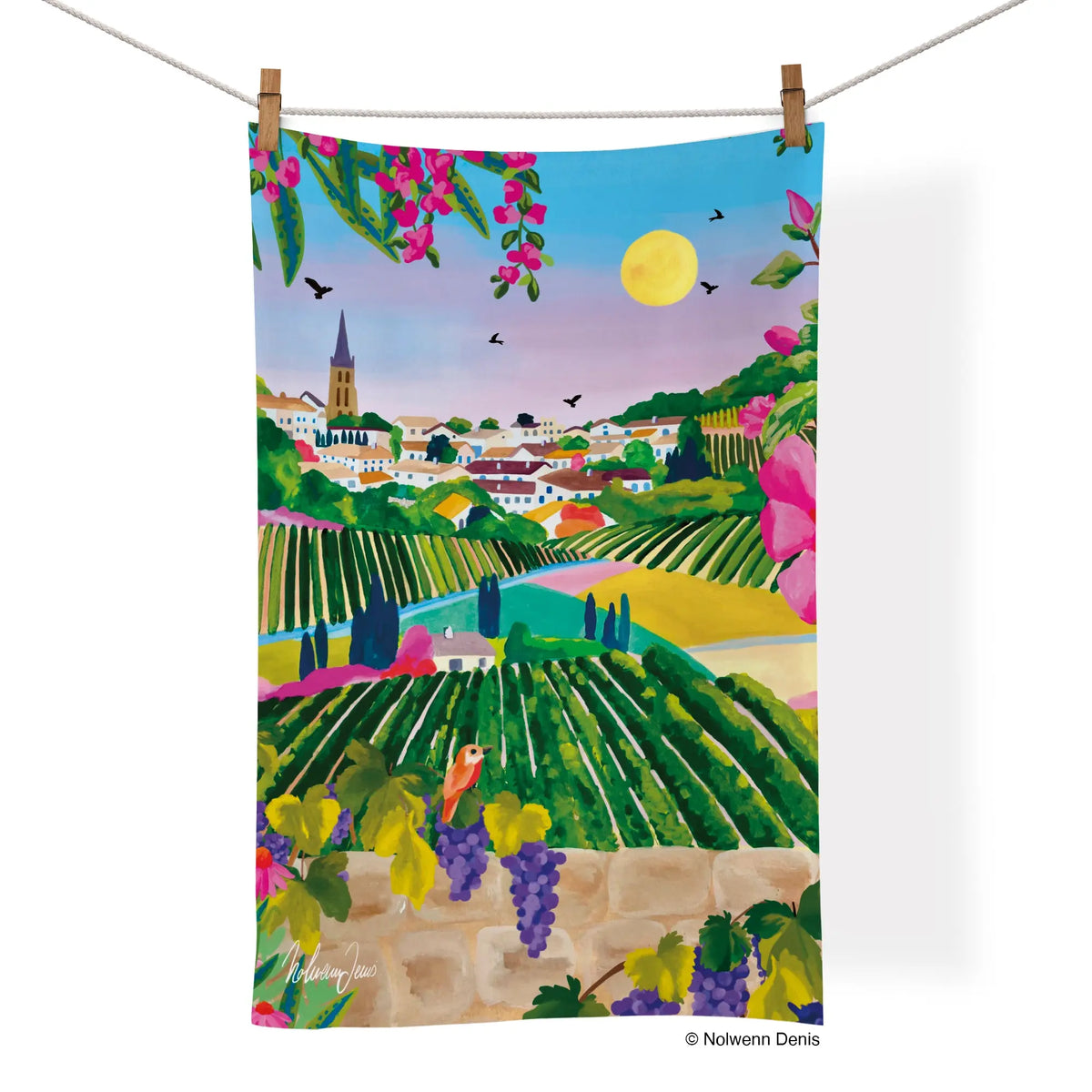 Cotton tea towel showing a colorful painting of a village with vineyards, a stone wall, grapes, and a small bird.