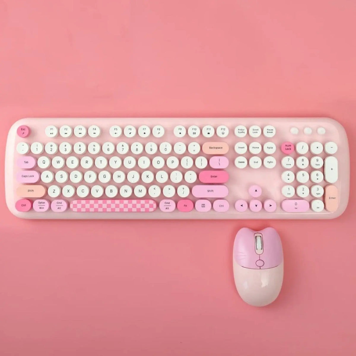 Pink wireless keyboard with round keys, checkered spacebar, and a cat-ear shaped matching pink computer mouse.