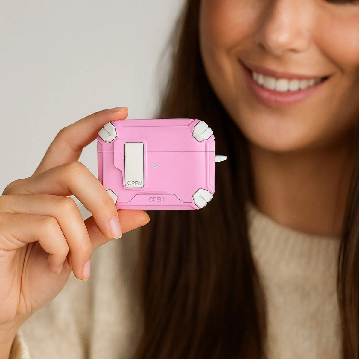 A person holds a pink, heavy-duty protective case with white corner bumpers and a secure locking latch mechanism.