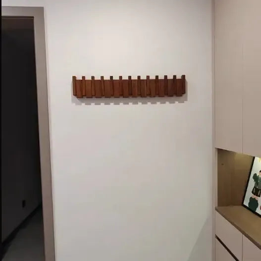 Perchero de pared de madera natural con diseño escandinavo, formado por listones abatibles en una base alargada.