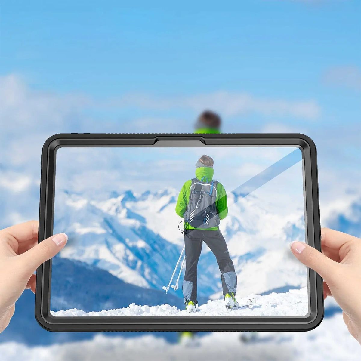 Hands holding a sleek, black waterproof tablet case with a clear, protective screen against a snowy mountain backdrop.