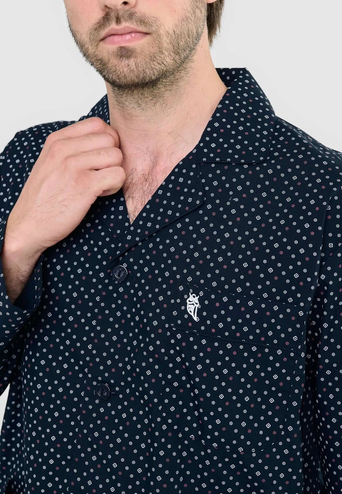 Pijama azul marino de hombre con estampado de pequeños cuadros y círculos, cuello de solapa, botones y logo bordado.