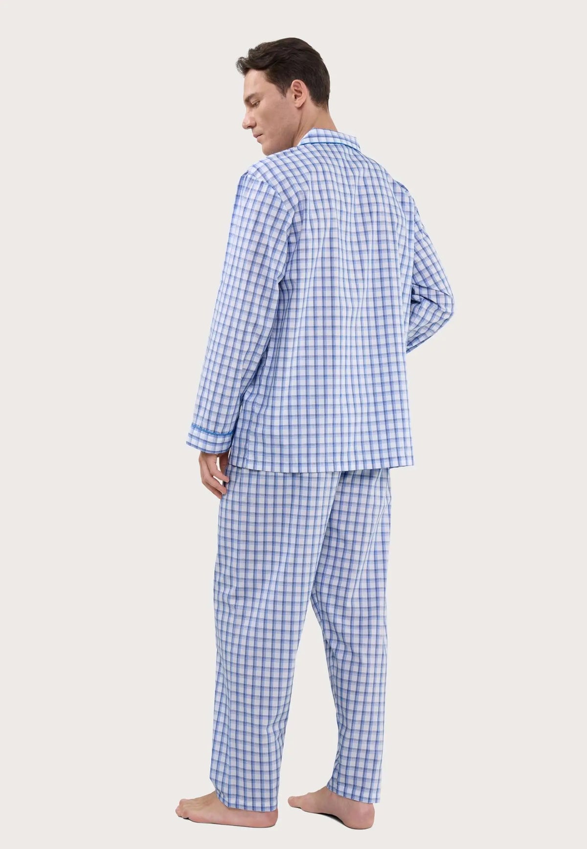 Hombre con pijama largo de cuadros azules y blancos, estilo camisa de manga larga con solapas, vista trasera.