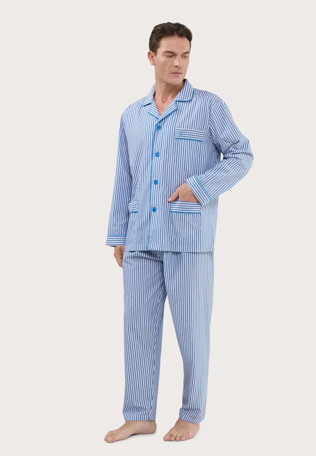 Pijama largo de hombre azul a rayas, con camisa de solapas, botones y bolsillos, tejido liso sobre modelo.