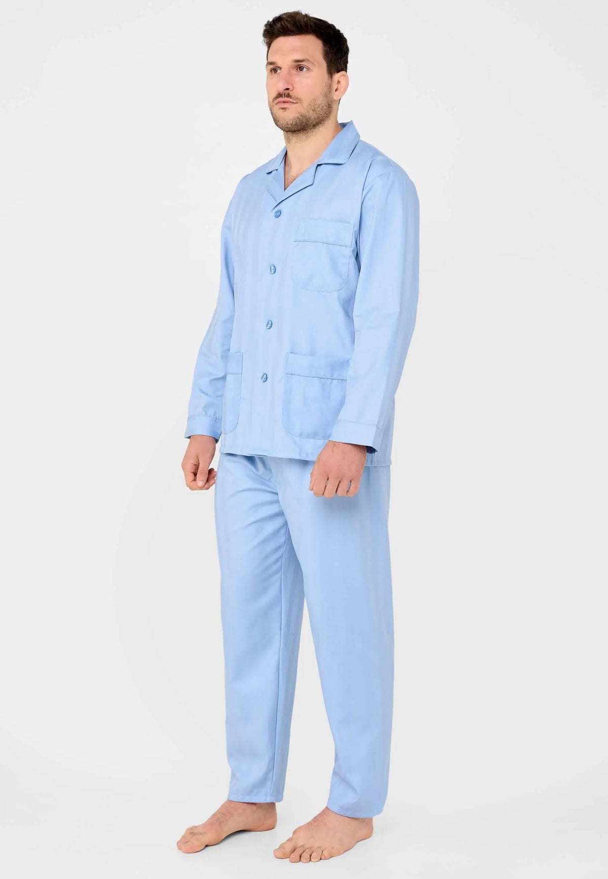 Hombre vistiendo pijama largo azul liso con cuello de solapa, botones frontales y bolsillos en tejido suave.