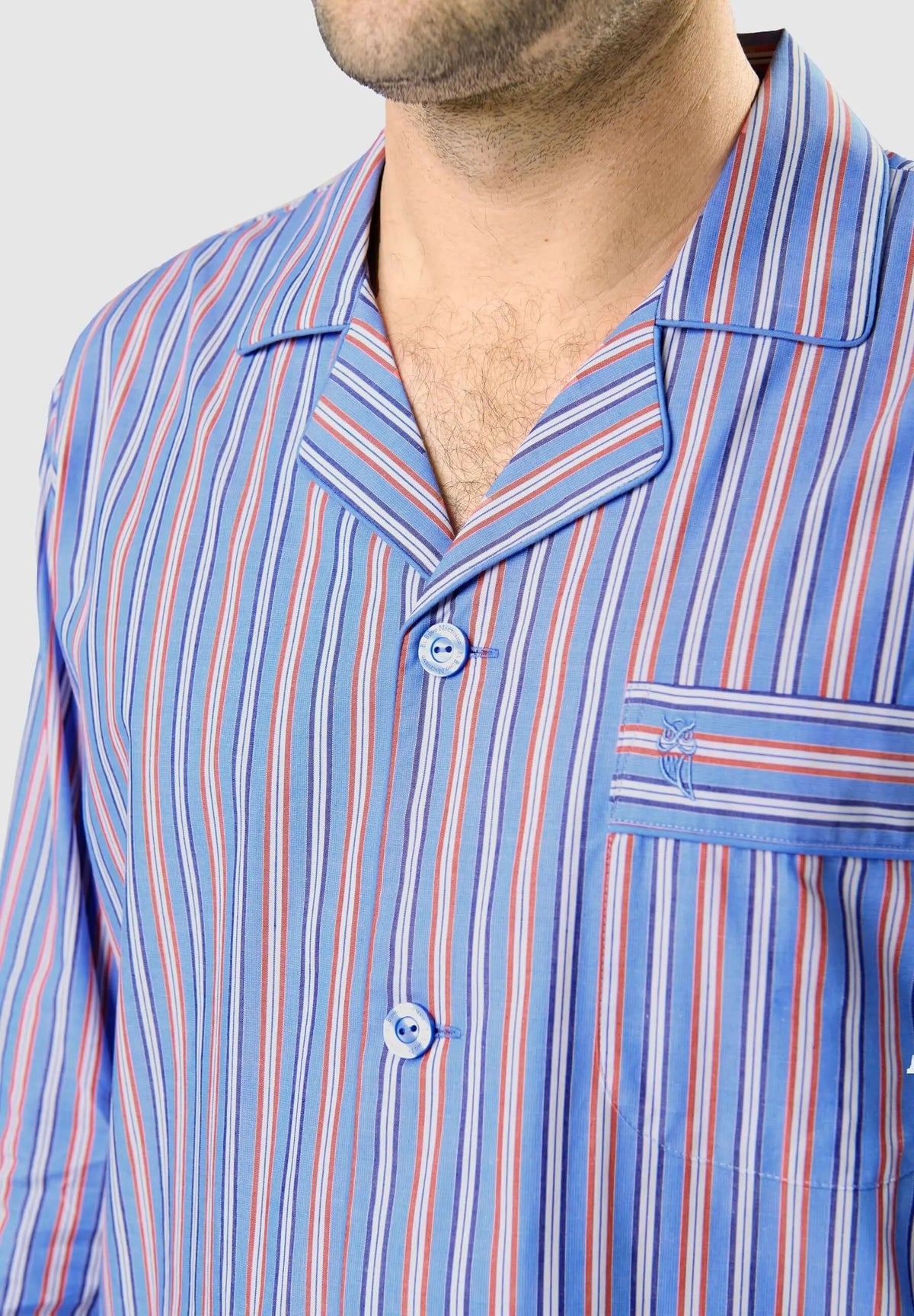 Pijama de hombre con cuello solapa, tejido de rayas azul, rojo y blanco, botones frontales y bolsillo con bordado búho.