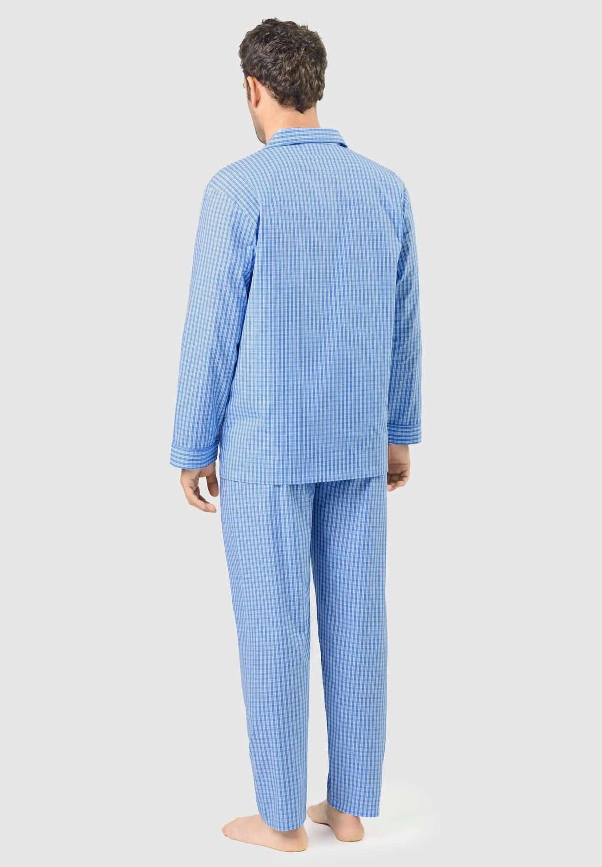 Hombre de espaldas con pijama largo de algodón azul con estampado de cuadros pequeños y cuello de solapa.