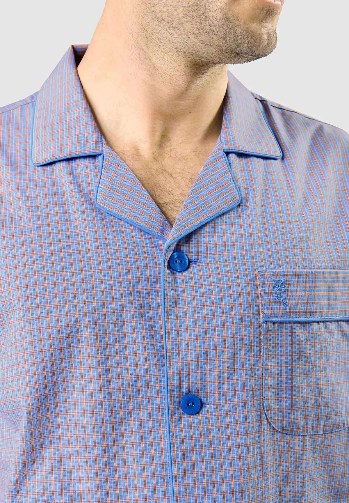 Pijama de hombre con cuello solapa, tejido de cuadros azules y naranjas, botones azules y bolsillo con bordado de búho.