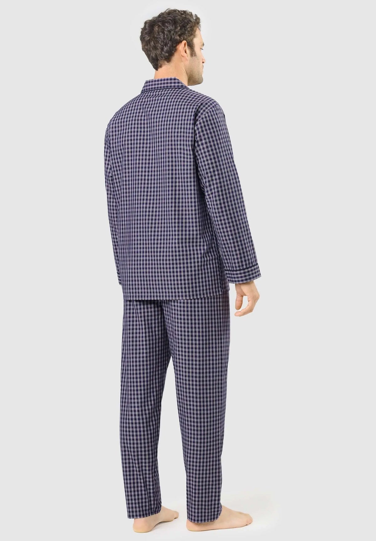 Hombre de espaldas vistiendo pijama largo de algodón azul con estampado de cuadros pequeños y cuello de solapa.