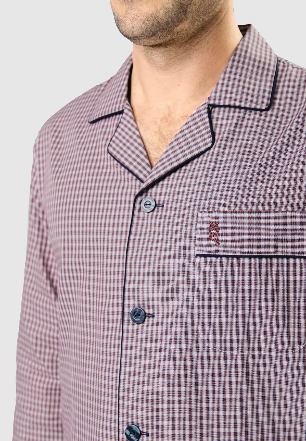 Pijama de hombre con cuello solapa, estampado de cuadros rojo y blanco, botones azul marino y bolsillo con logo bordado.