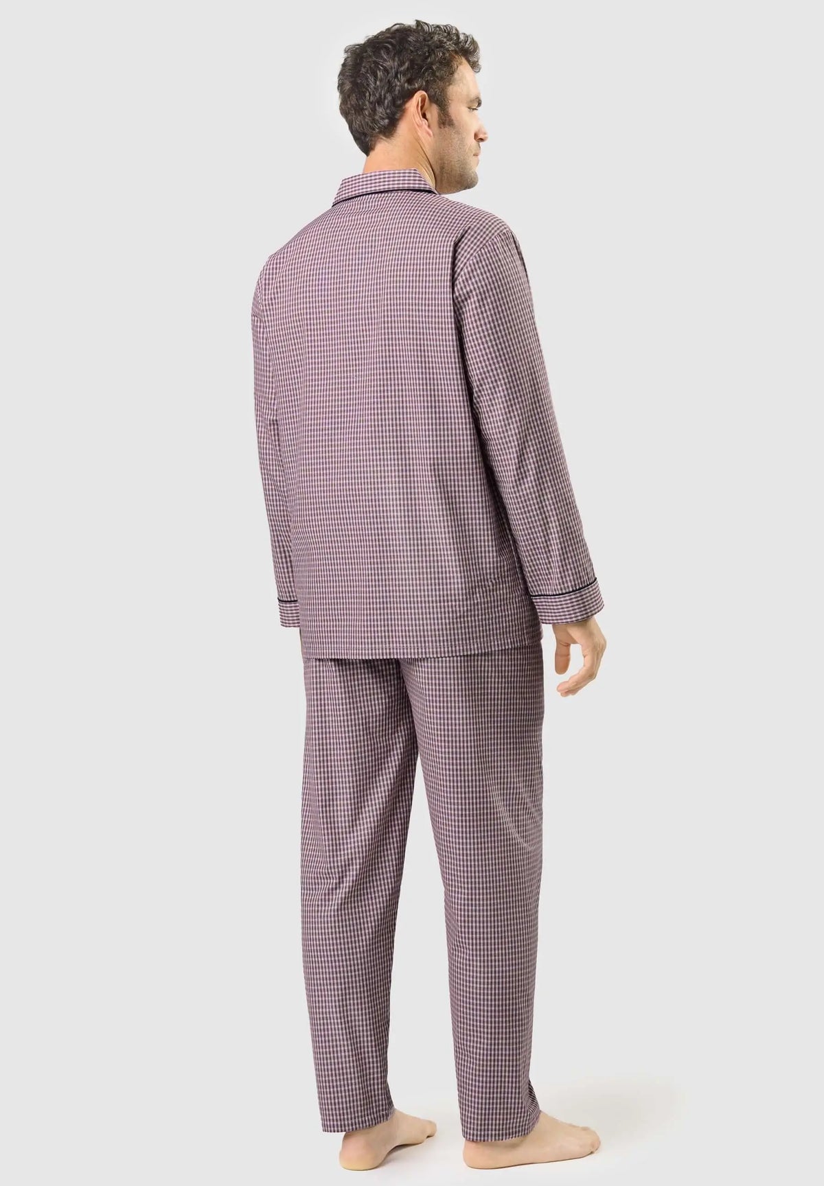 Hombre de espaldas vistiendo pijama largo de cuadros rojos y azul marino con solapa, estilo clásico en algodón.