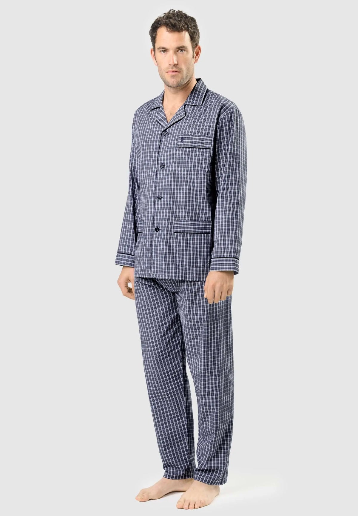 Pijama de hombre largo, azul marino a cuadros blancos, con camisa de solapa, botones y bolsillo, sobre un modelo.