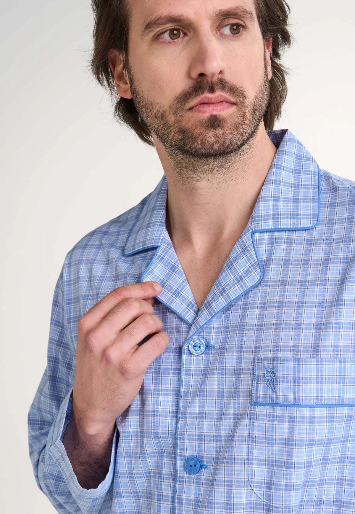 Hombre con pijama de cuadros azul y blanco, tejido popelín, cuello de solapa, botones y bolsillo bordado con un búho.