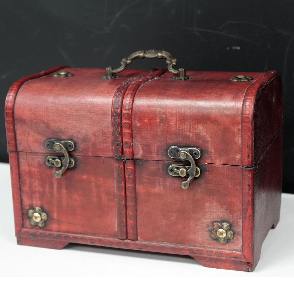 Caja de madera roja vintage con herrajes dorados y detalle de costura, ideal para decoración o almacenamiento.