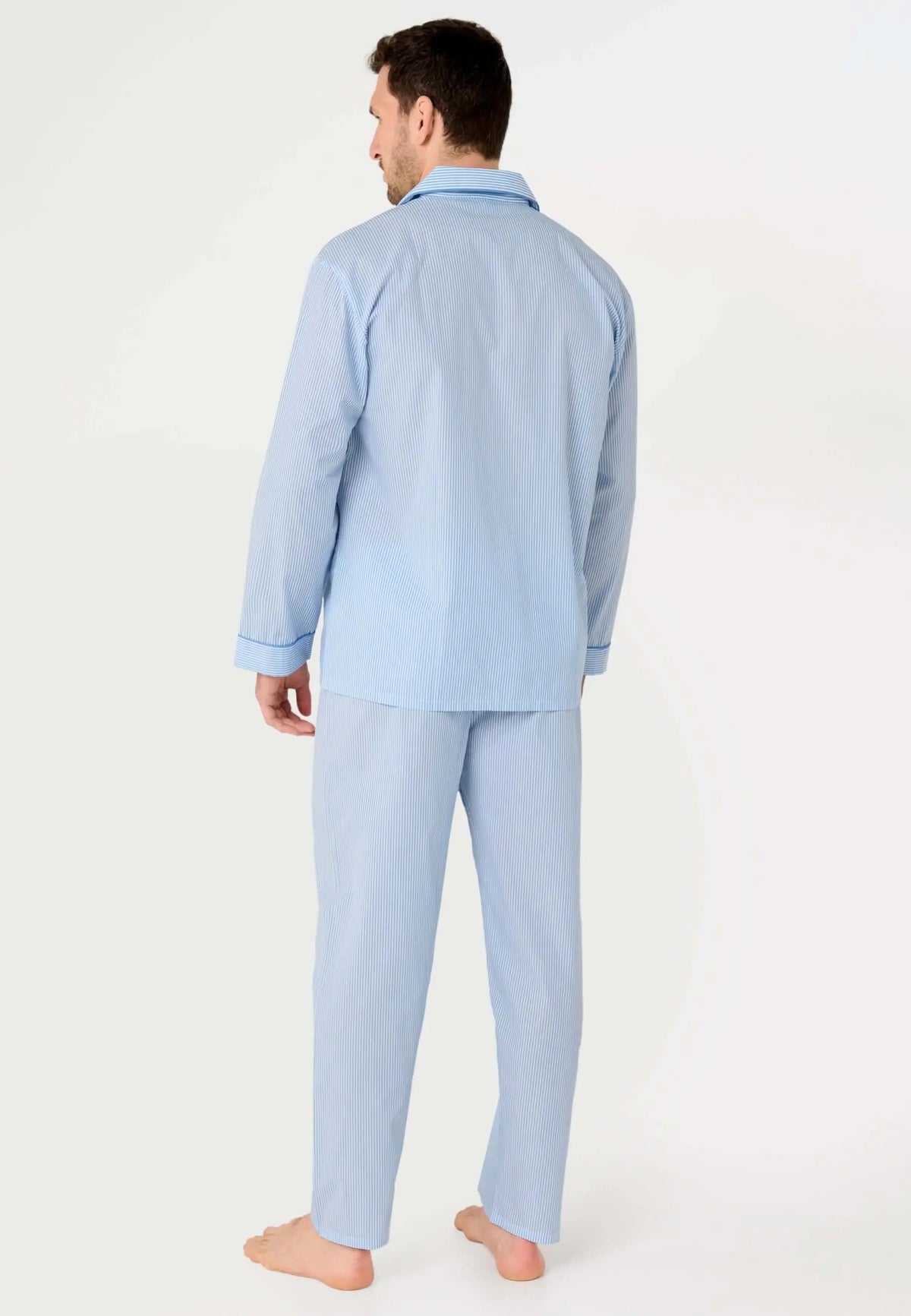 Hombre de espaldas vistiendo pijama largo de popelín azul con estampado de rayas finas y cuello de solapa.