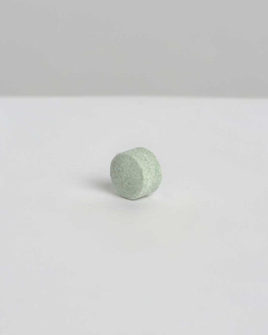 Refill Banbu: pastilla de dentífrico ecológica de color verde claro, con textura compacta sobre fondo gris claro neutro.