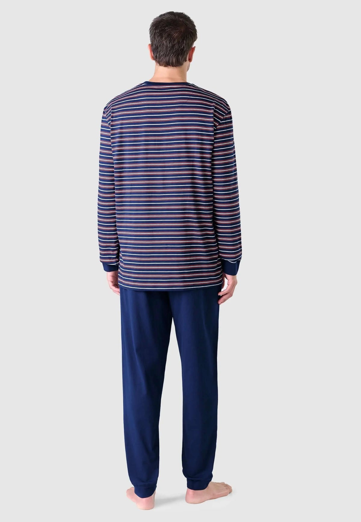 Hombre de espaldas con pijama de punto: camiseta de rayas horizontales y pantalón azul liso de corte recto.