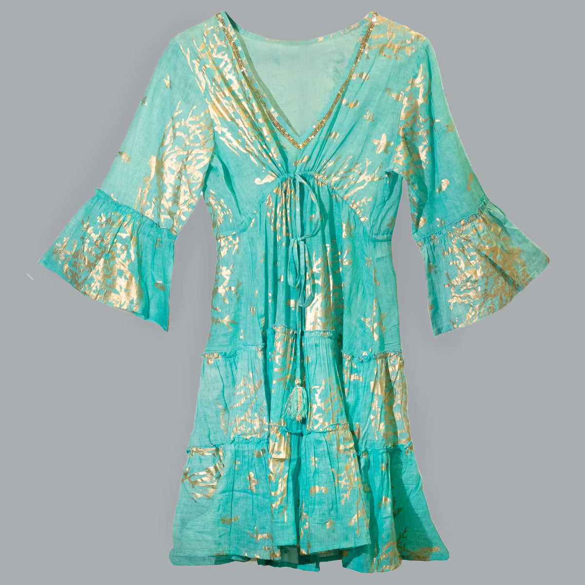 Vestido corto turquesa con estampado de corales dorados, cuello en V, mangas acampanadas y cordón con borlas.
