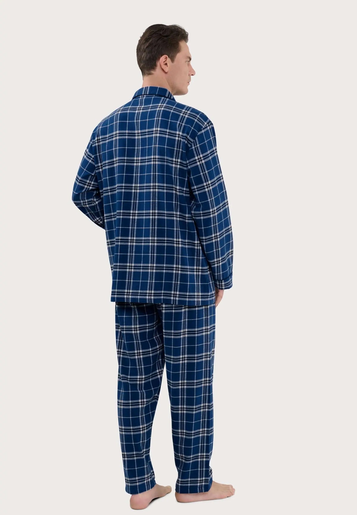Hombre vistiendo pijama largo de cuadros azul y blanco con cuello de solapa, visto de espaldas sobre fondo neutro.