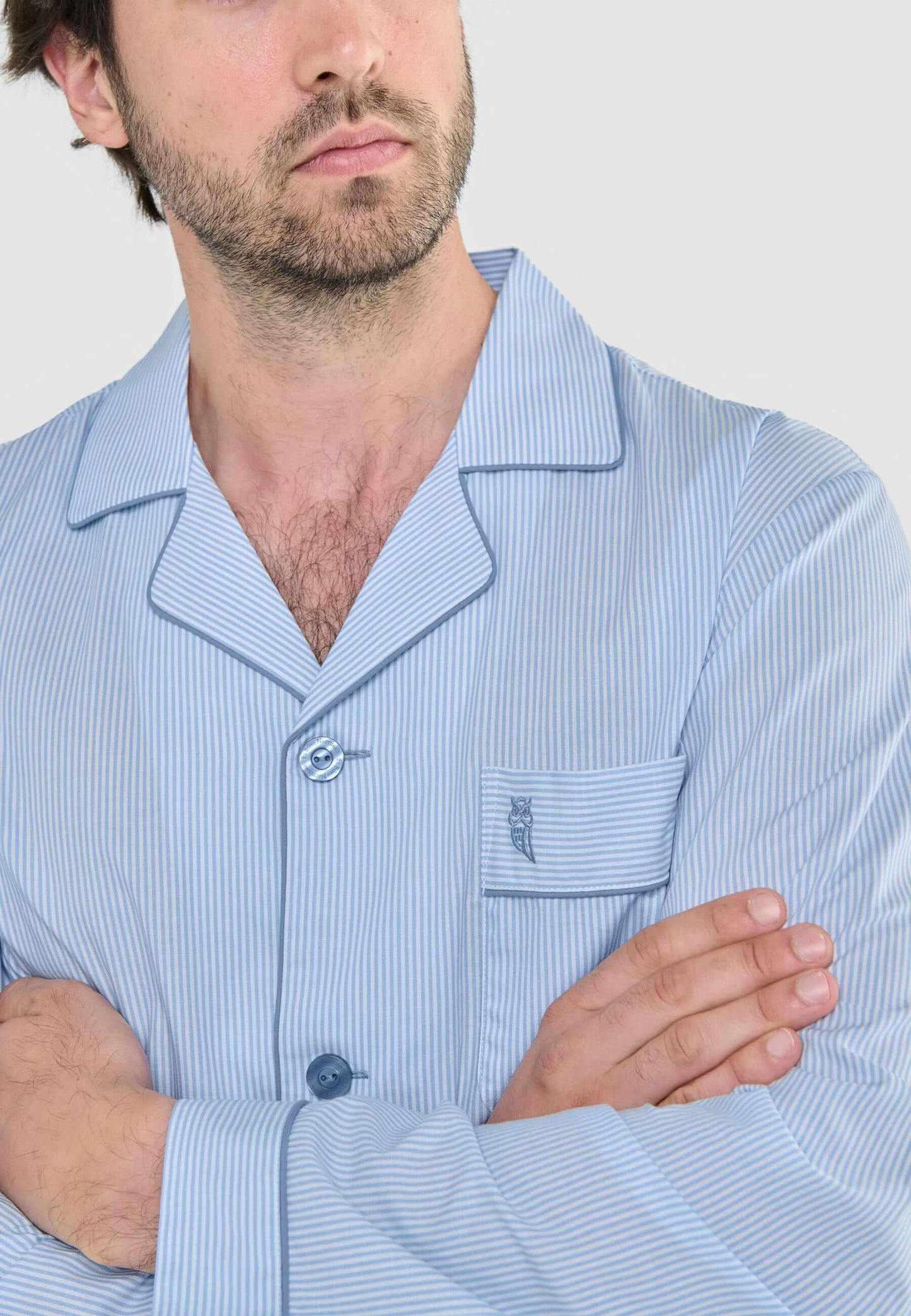 Pijama de hombre de rayas celestes y blancas, con solapas, bolsillo y botones, modelo con tejido fino de algodón.