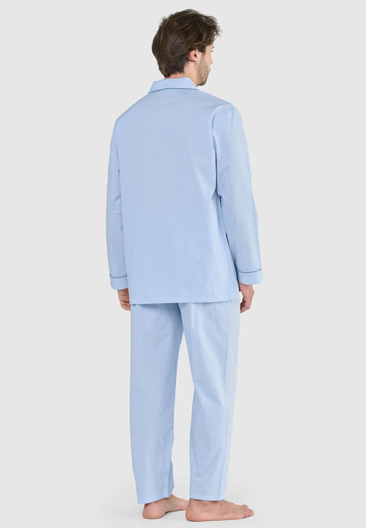 Pijama largo de hombre azul celeste a rayas finas, con solapas y remates en puños, puesto por un modelo de espaldas.