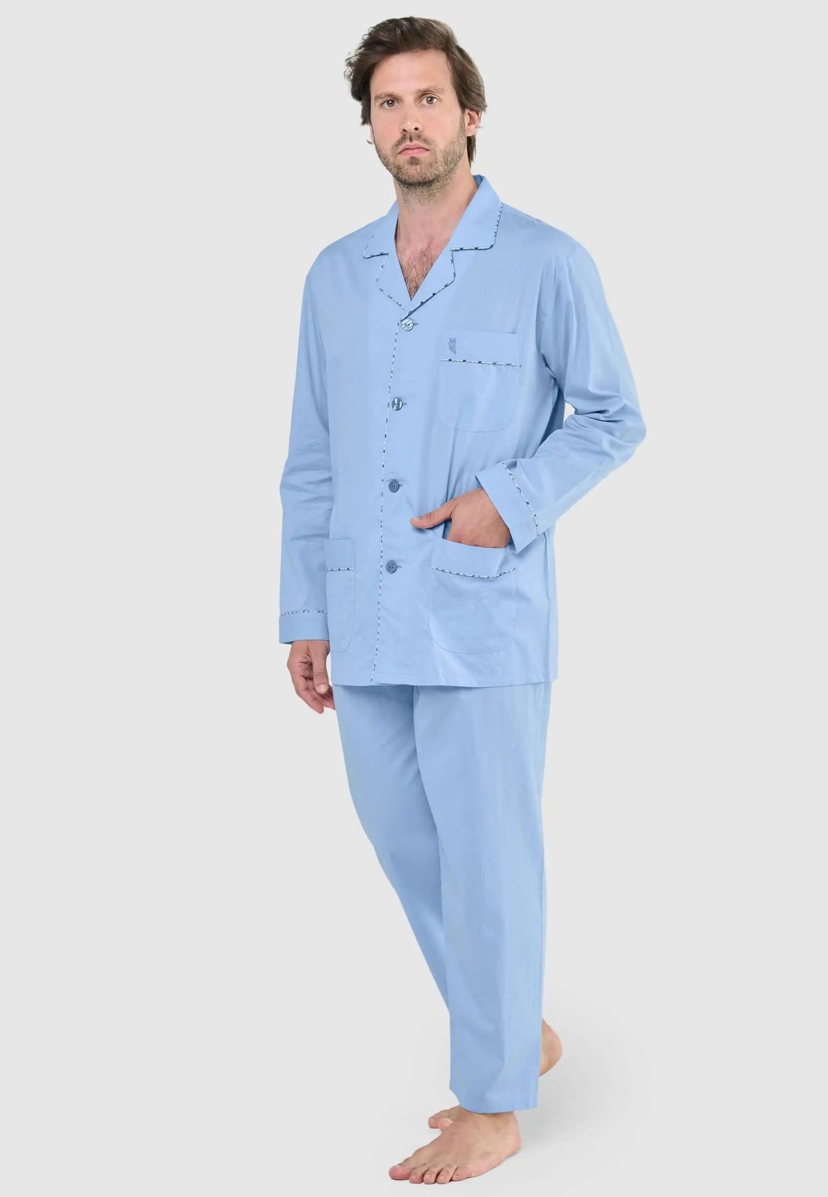 Pijama de hombre azul claro con botones, cuello de solapa y bolsillos, lucido por un modelo de pie.