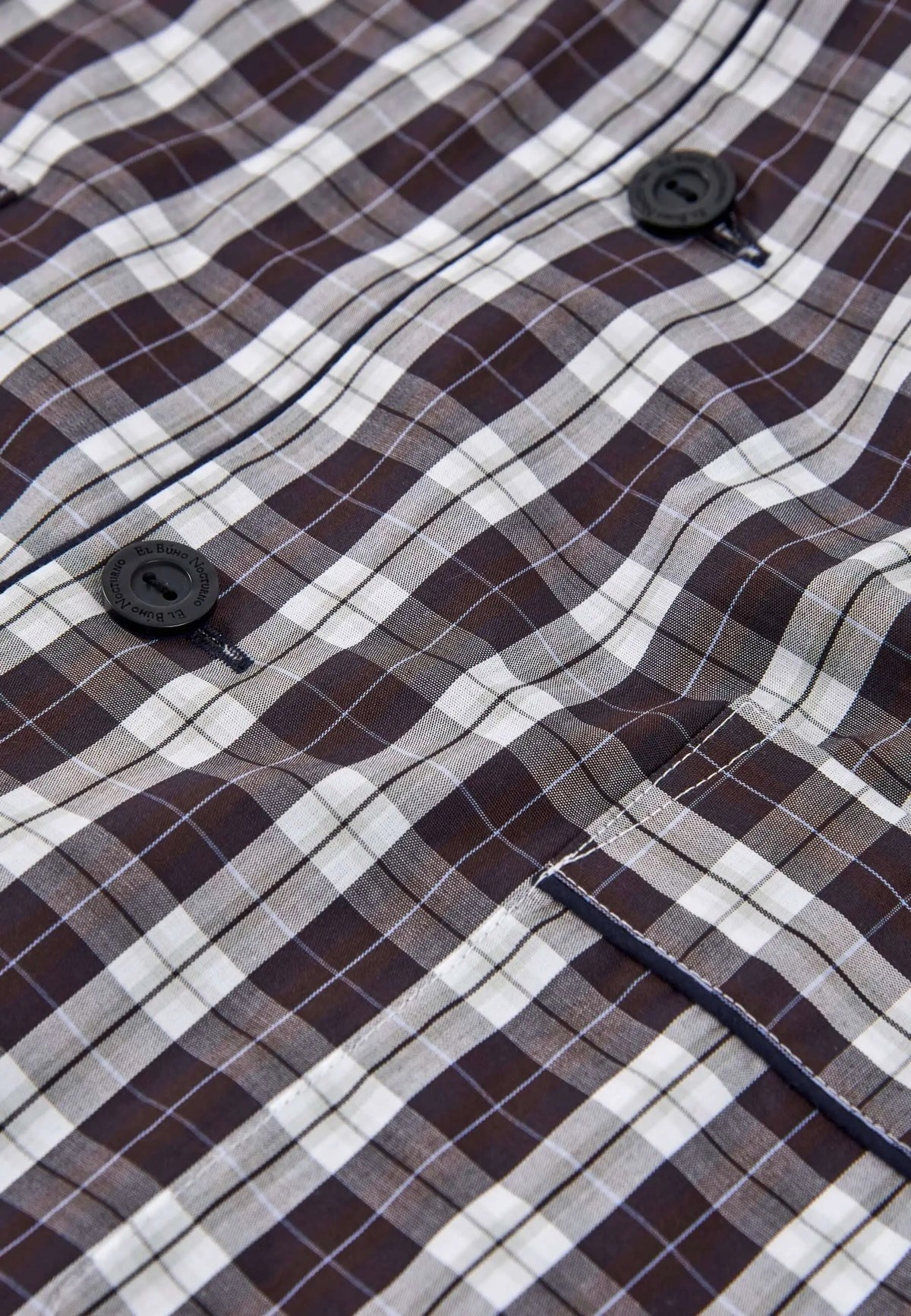 Pijama de hombre de popelín a cuadros en tonos marrón y blanco con botones negros grabados y bolsillo frontal.