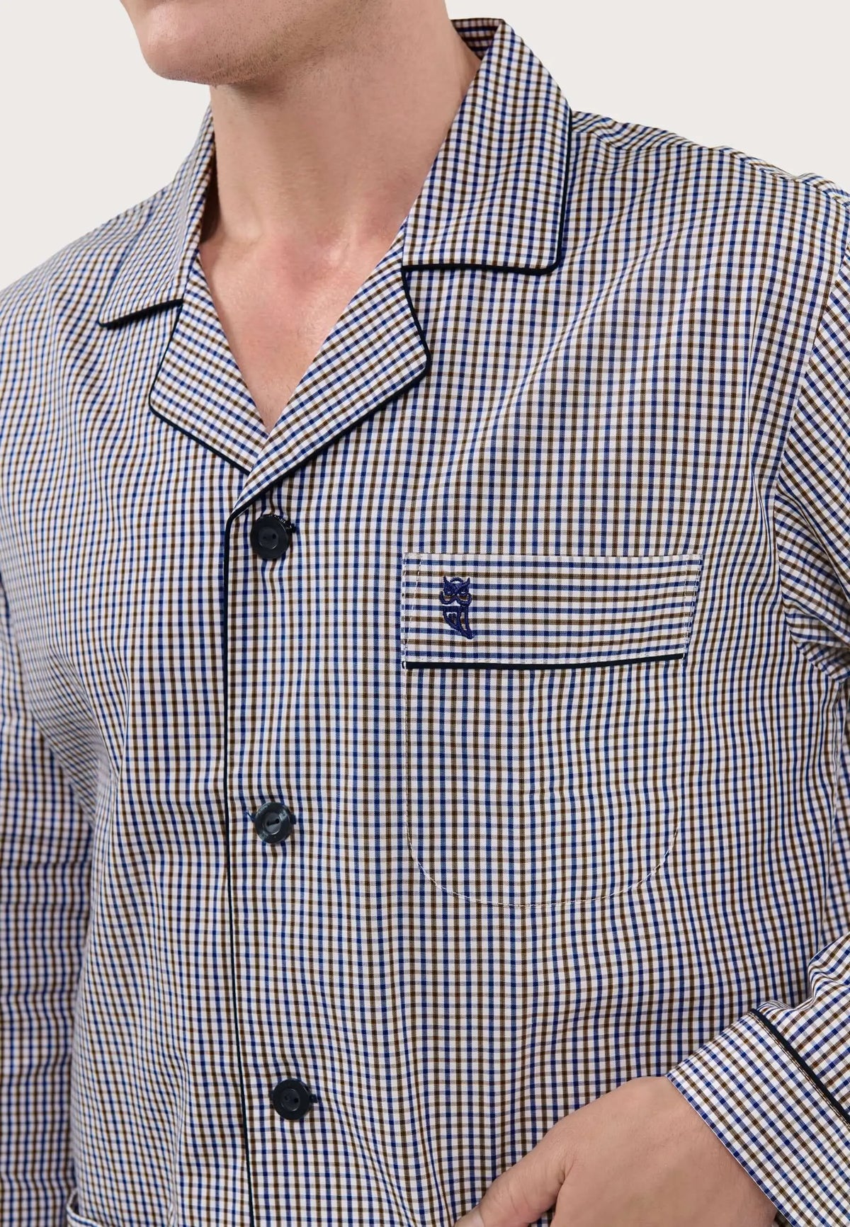 Pijama de hombre con cuello solapa, estampado de cuadros beige y azul, botones oscuros, bolsillo y logo de búho bordado.