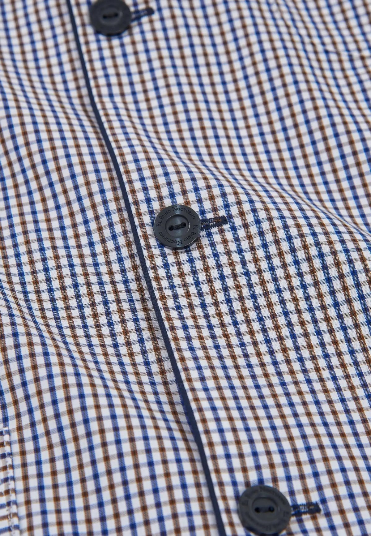 Pijama de hombre con estampado de cuadros azul y marrón, botones oscuros grabados y ribete vertical azul marino.