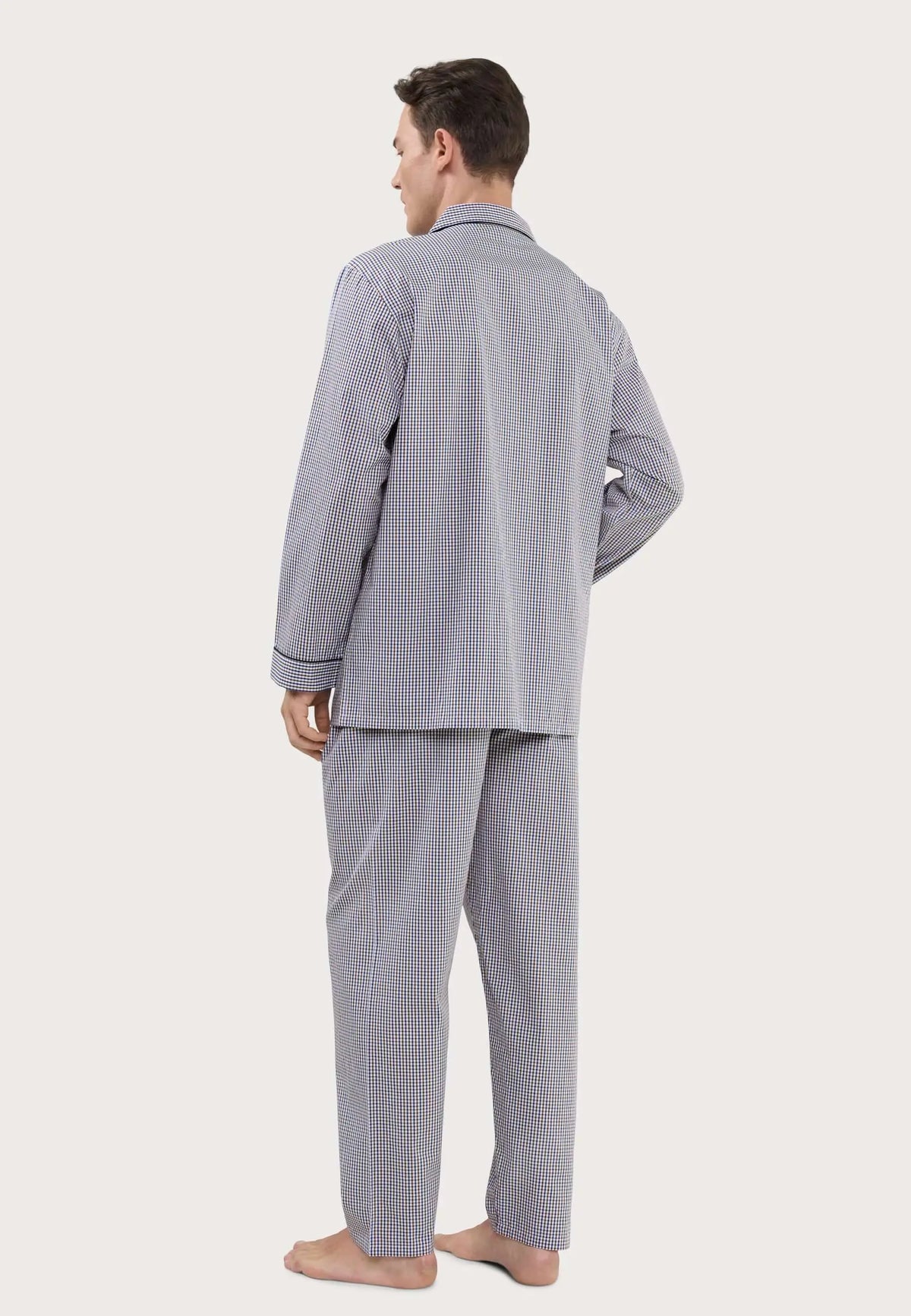 Hombre de espaldas vistiendo pijama largo de cuadros pequeños azules y beige con cuello de solapa y ribete oscuro.