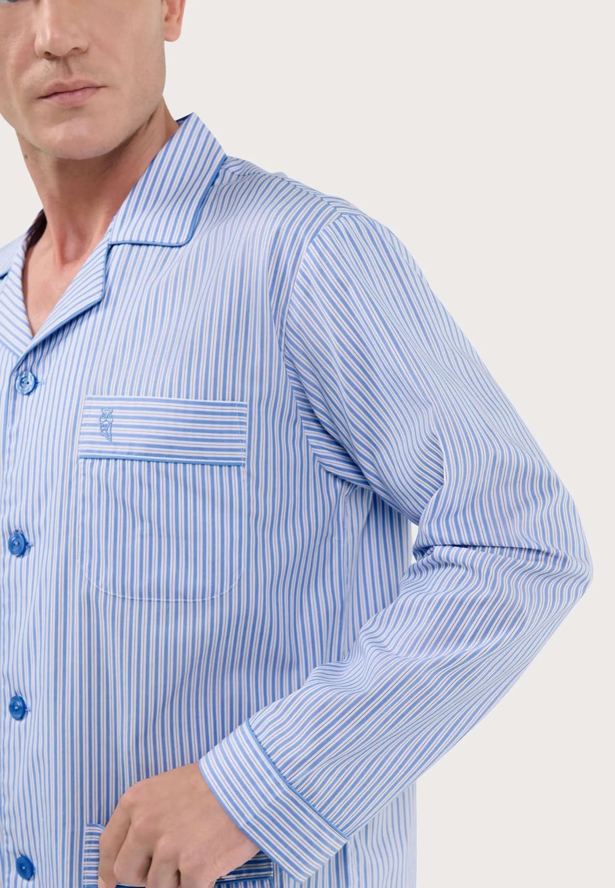 Pijama de hombre de rayas azul y blanco con solapa, botones frontales y bolsillo bordado con logo.