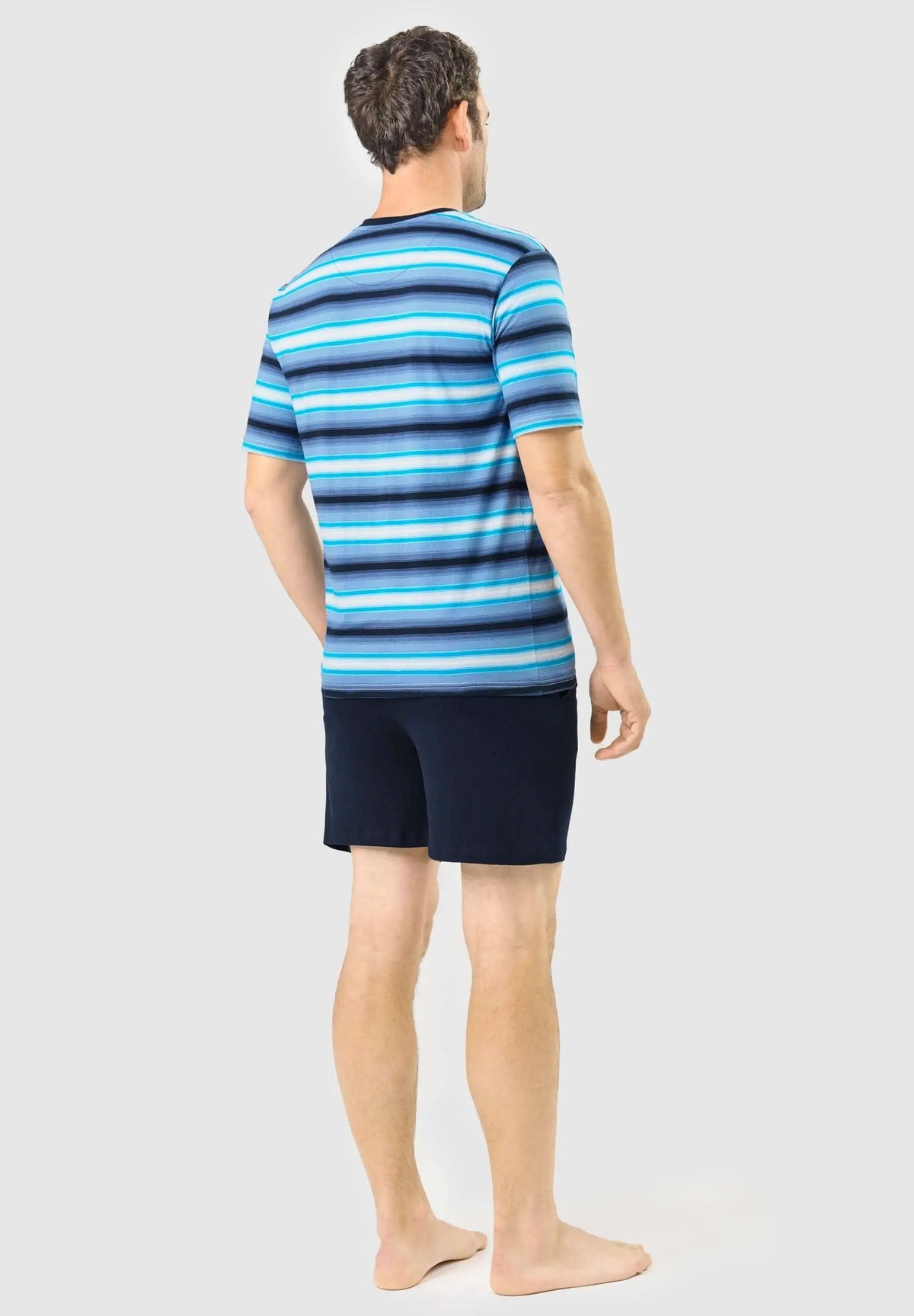 Pijama hombre verano: camiseta manga corta rayas azules y pantalón corto liso azul marino. Modelo de espaldas.